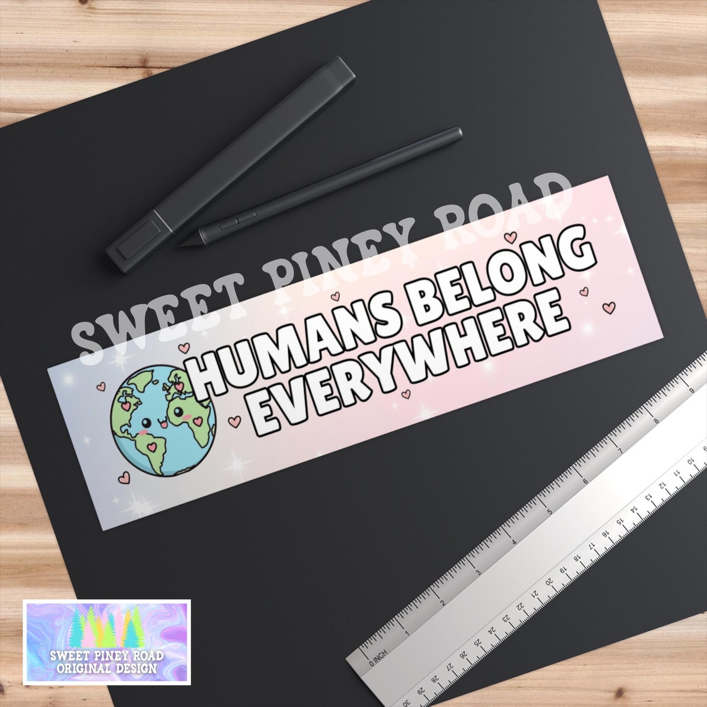 Close-up of a pastel “Humans Belong Everywhere” vinyl sticker showing smooth print quality and cute, colorful design details.