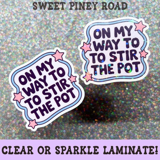 Funny pastel sticker featuring the phrase On My Way to Stir the Pot surrounded by pink stars and decorative accents on a clear laminate finish.