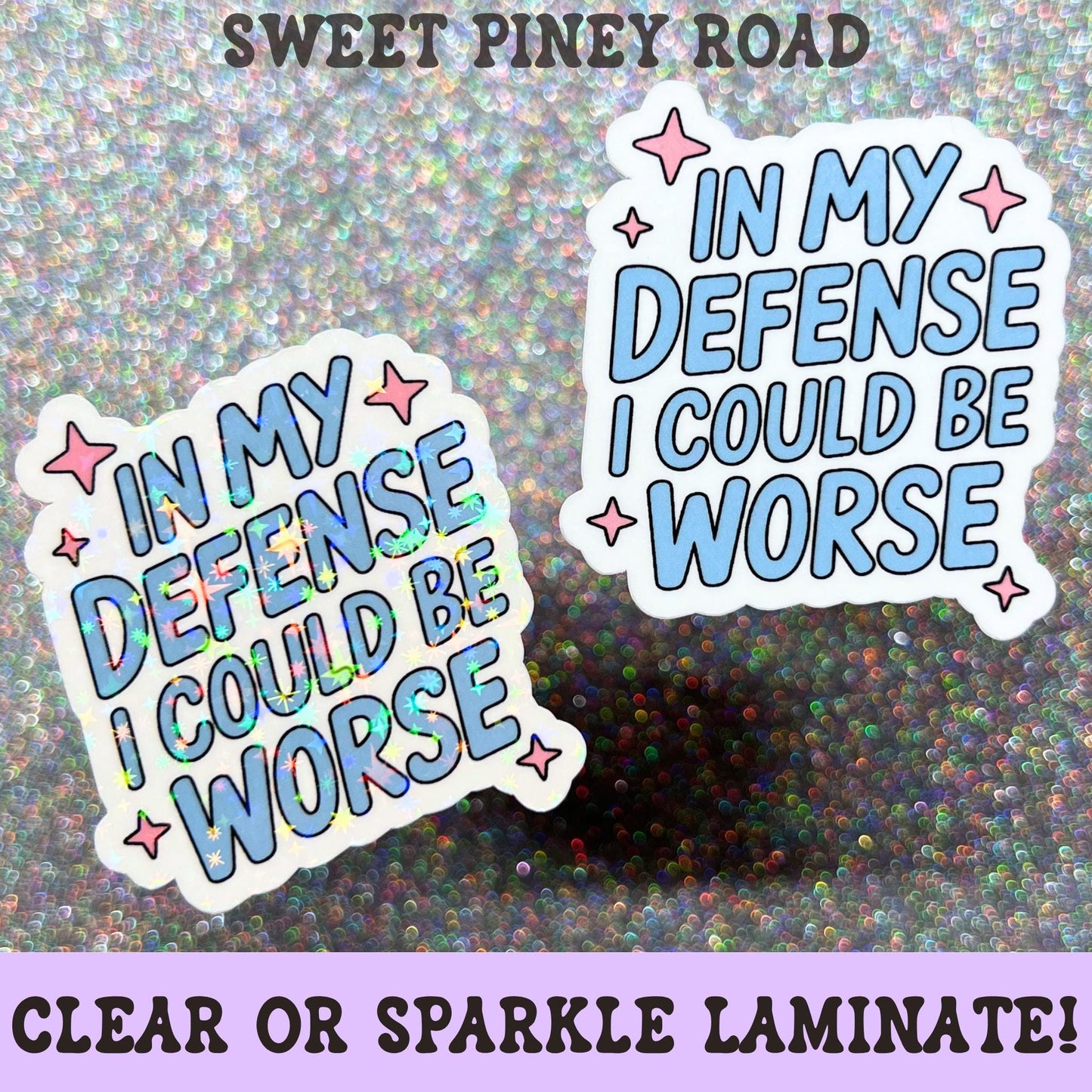 Funny pastel blue sticker featuring the phrase In My Defense I Could Be Worse with pink star accents and a playful sarcastic design.