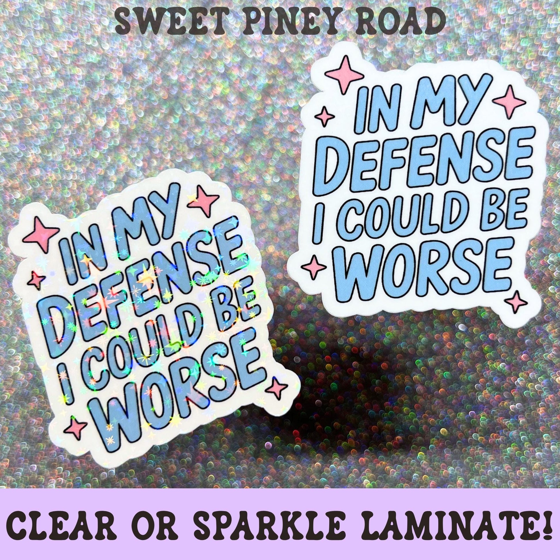 Funny pastel blue sticker featuring the phrase In My Defense I Could Be Worse with pink star accents and a playful sarcastic design.