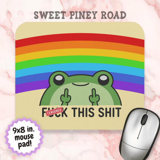 Funny mouse pad featuring a smiling green frog giving double middle fingers beneath a colorful rainbow with the phrase "Fuck This Shit." Humorous desk accessory with bright rainbow colors, sarcastic humor, and playful cartoon artwork designed for office and home workspaces.