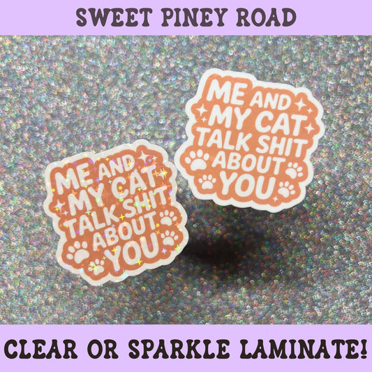 Funny cat sticker with the phrase "Me And My Cat Talk Shit About You" in orange lettering with paw prints, perfect for cat lovers and sarcastic humor fans.