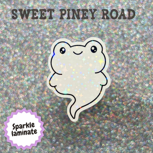 Cute kawaii ghost toad sticker featuring a smiling white ghost shaped like a frog or toad with simple black eyes and a whimsical Halloween aesthetic.