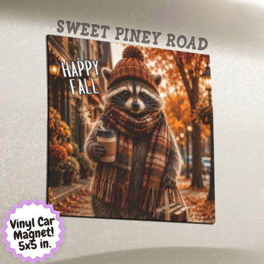 Cute raccoon wearing a knit beanie and plaid scarf while carrying coffee and books on a colorful autumn street with fall leaves and cozy seasonal scenery.