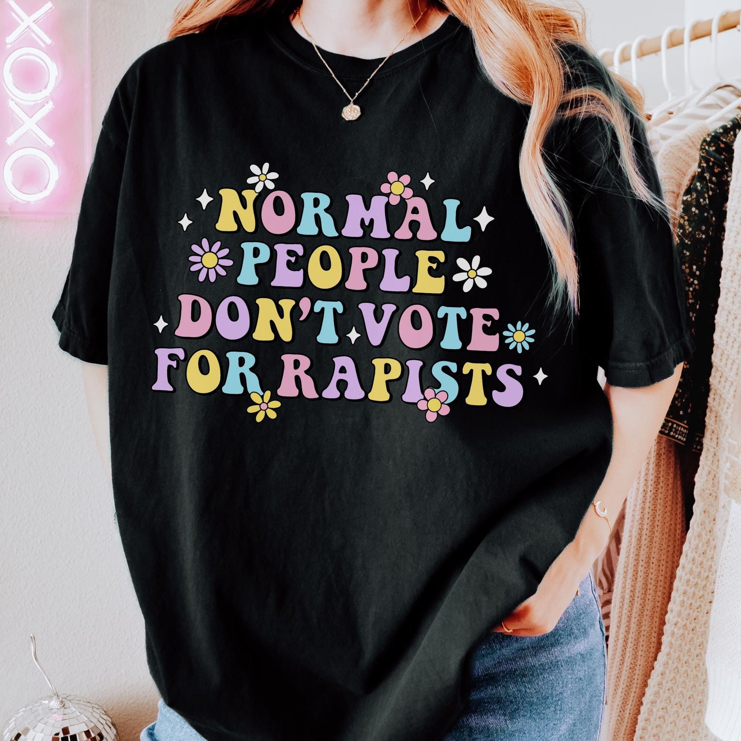 Colorful retro-style typography design featuring the phrase "Normal People Don't Vote For Rapists" surrounded by flowers and decorative accents on a black background.