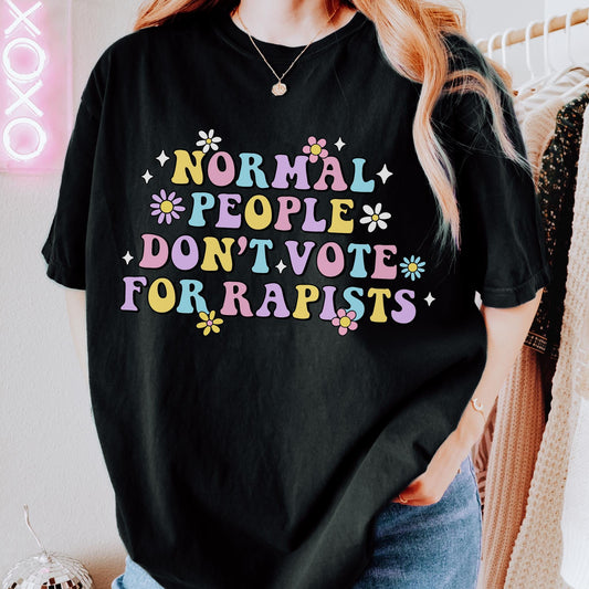Colorful retro-style typography design featuring the phrase "Normal People Don't Vote For Rapists" surrounded by flowers and decorative accents on a black background.