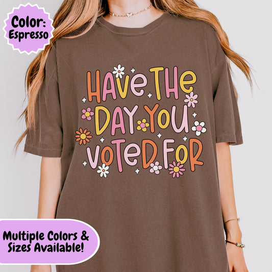 Retro-style typography shirt design featuring the phrase "Have The Day You Voted For" in colorful pastel letters surrounded by flowers and decorative accents, humorous anti-Trump political graphic.