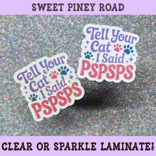 Colorful sticker reading "Tell Your Cat I Said Pspsps" with cat paw prints and playful lettering on a holographic sparkle background, funny gift for cat lovers and pet parents.