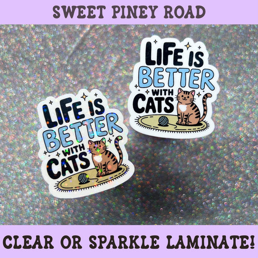 Cute cat sticker reading "Life Is Better With Cats" featuring a smiling tabby cat with a ball of yarn, perfect for laptops, tumblers, water bottles, planners, journals, and e-readers.